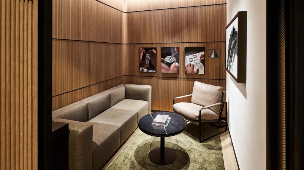 木製の壁と床、ソファ、椅子、丸いテーブル、3つの絵画、ランプ、アートワークのあるモダンなインテリアです。